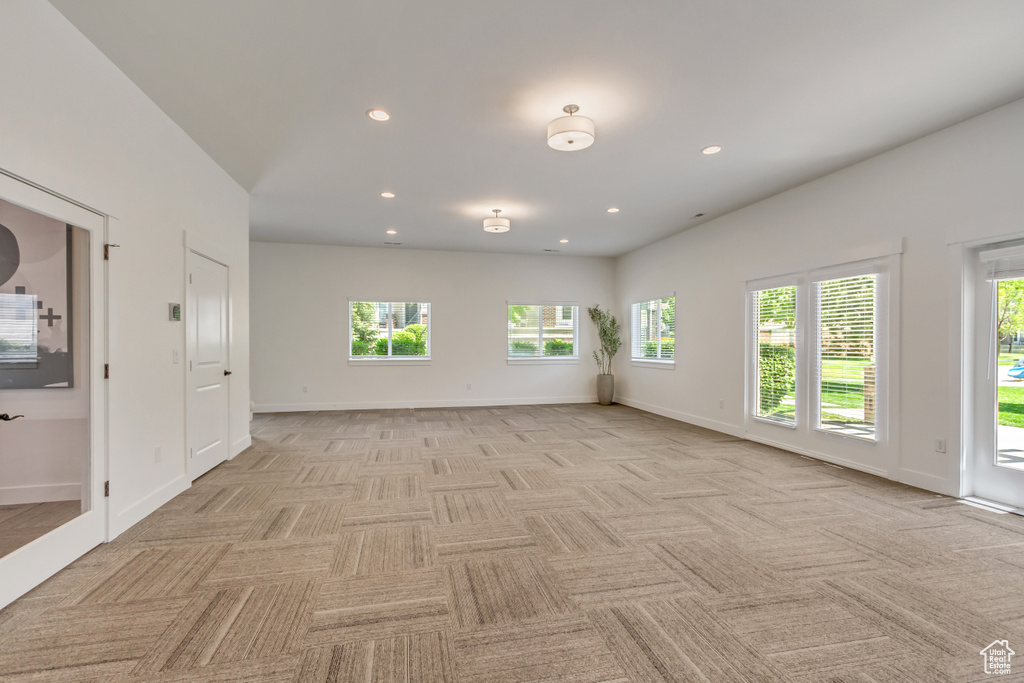 Spare room featuring healthy amount of natural light, light colored carpet, recessed lighting, and baseboards