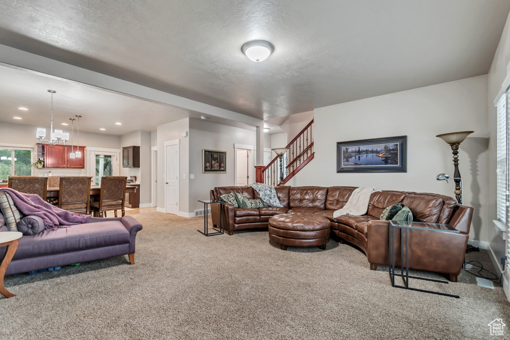 Living area with a notable chandelier, recessed lighting, baseboards, stairs, and light carpet