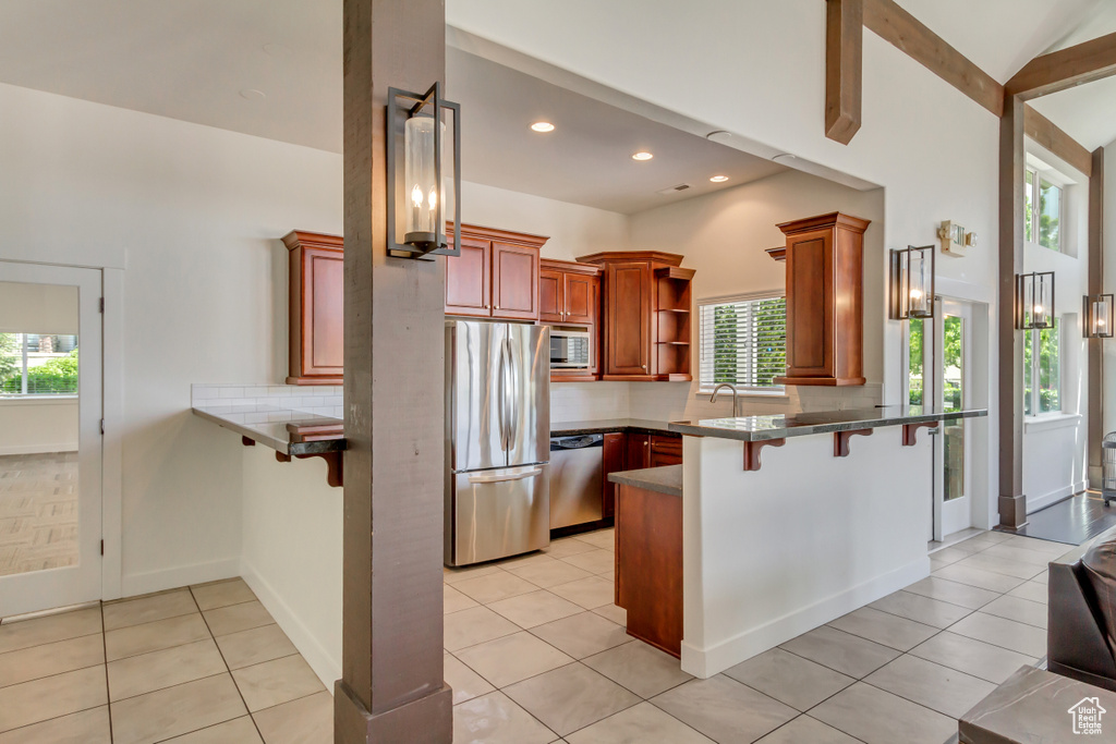 Kitchen with stainless steel appliances, a peninsula, plenty of natural light, a breakfast bar area, and recessed lighting