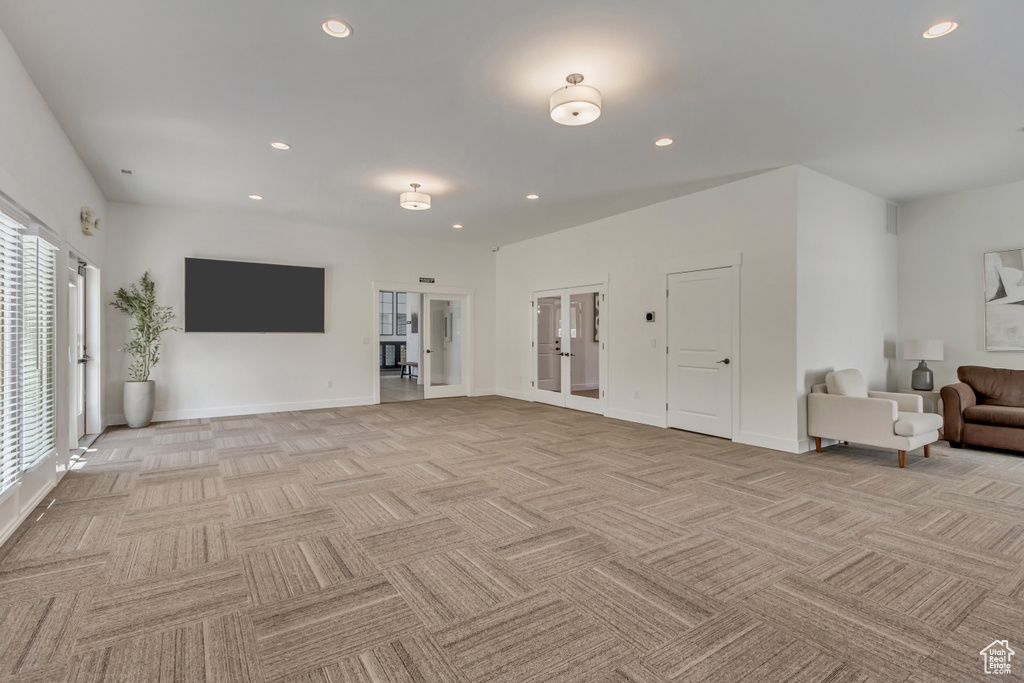 Unfurnished living room featuring light carpet, french doors, recessed lighting, and baseboards