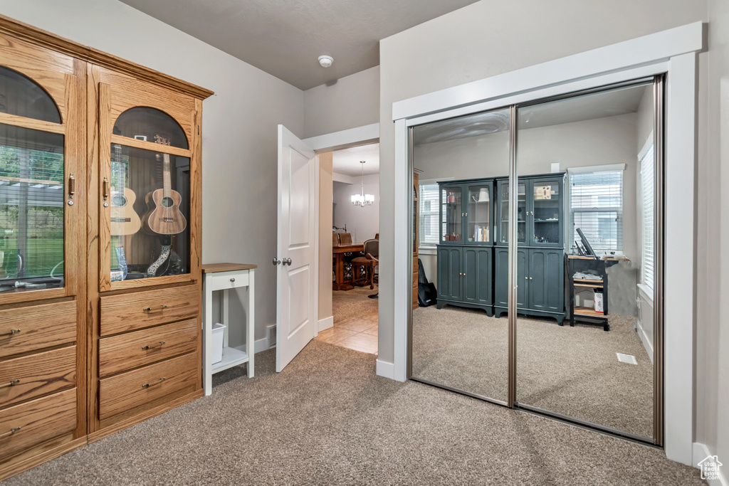 Carpeted bedroom with a closet, baseboards, and a notable chandelier