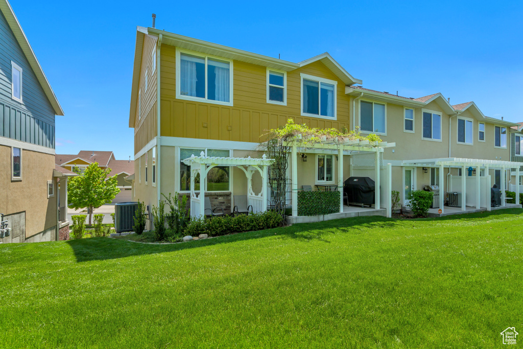 Rear view of property with a pergola, central AC, a lawn, and a patio
