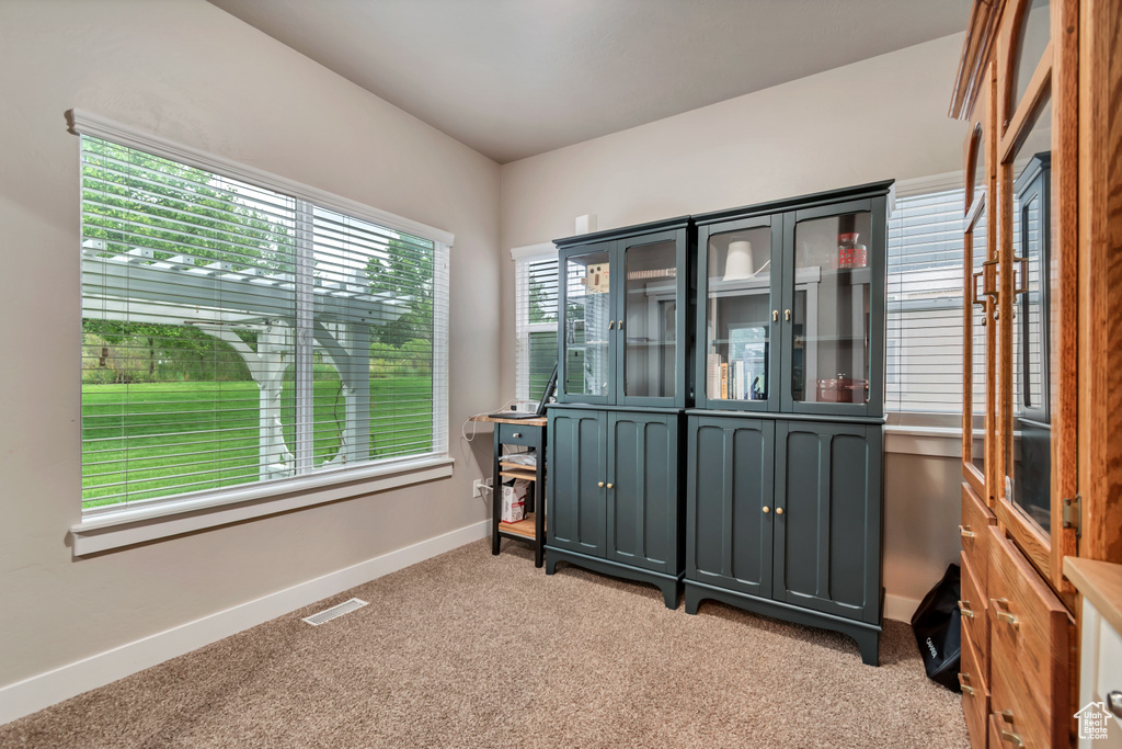 Empty room with light colored carpet, visible vents, and baseboards