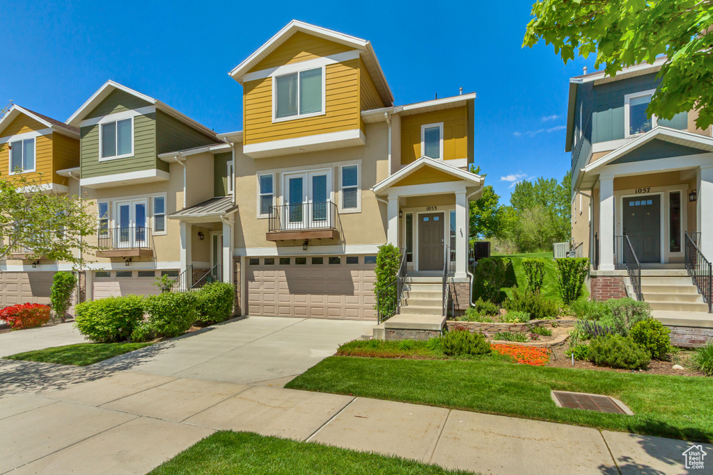 View of front of house with french doors, stucco siding, an attached garage, and driveway