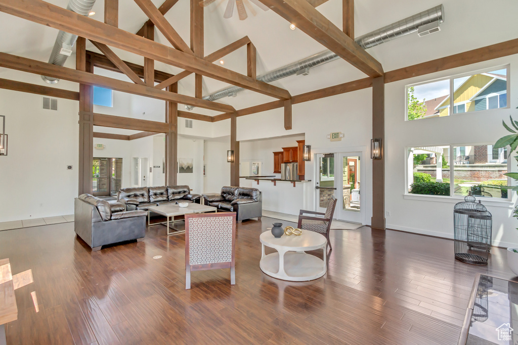 Living room featuring high vaulted ceiling, healthy amount of natural light, wood finished floors, and beam ceiling