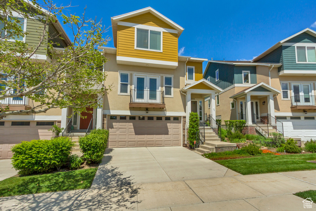 Multi unit property with french doors, a garage, stucco siding, a balcony, and concrete driveway