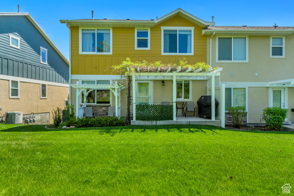 Rear view of house with a pergola, central AC, a patio area, and a lawn
