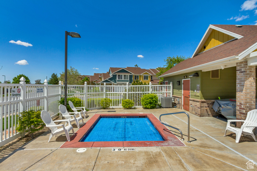 Community pool featuring central AC, a patio, fence, and a residential view