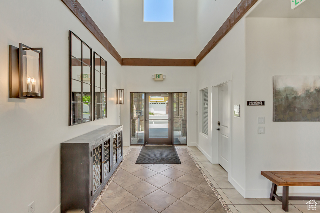 Foyer featuring baseboards, light tile patterned floors, and a towering ceiling
