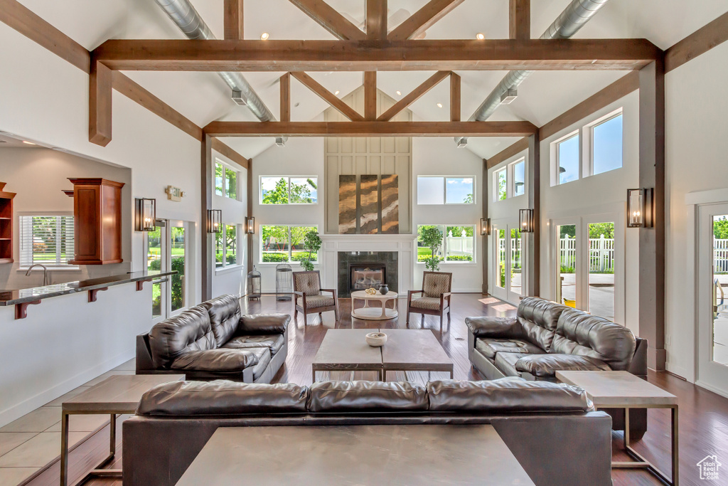 Living room with high vaulted ceiling, beamed ceiling, a tile fireplace, and baseboards