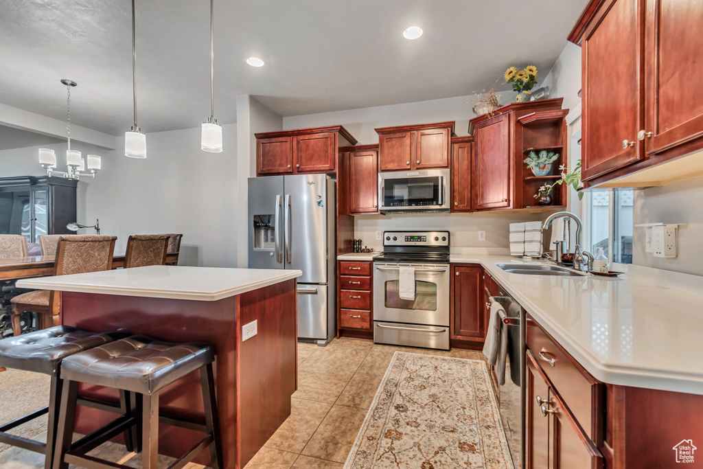 Kitchen with a sink, open shelves, recessed lighting, a kitchen bar, and appliances with stainless steel finishes