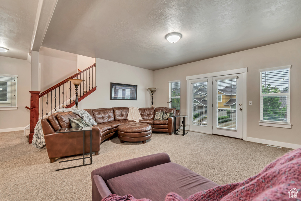 Carpeted living room with stairway, a textured ceiling, a wealth of natural light, and baseboards