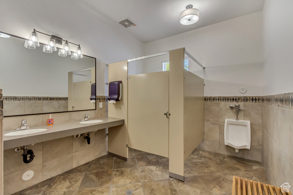 Bathroom featuring tile walls, a sink, a walk in shower, and wainscoting
