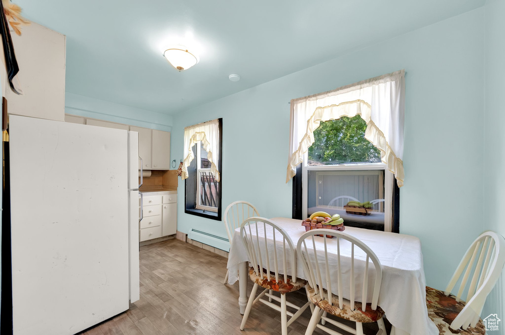 Dining area featuring a baseboard radiator, plenty of natural light, and light wood finished floors