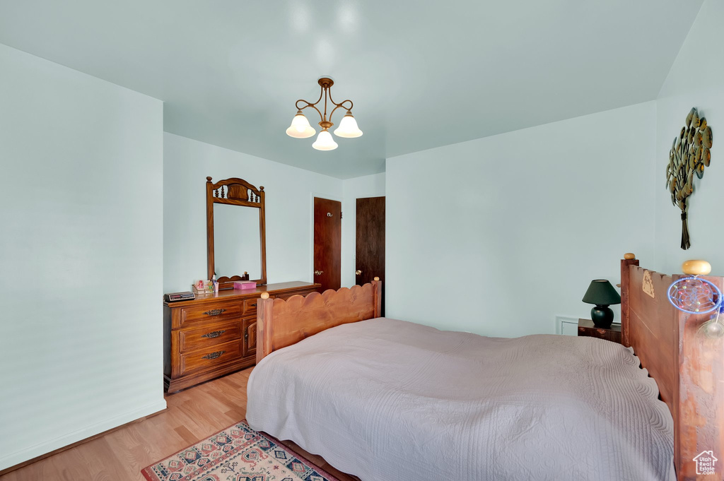 Bedroom with a chandelier, light wood-style floors, and baseboards