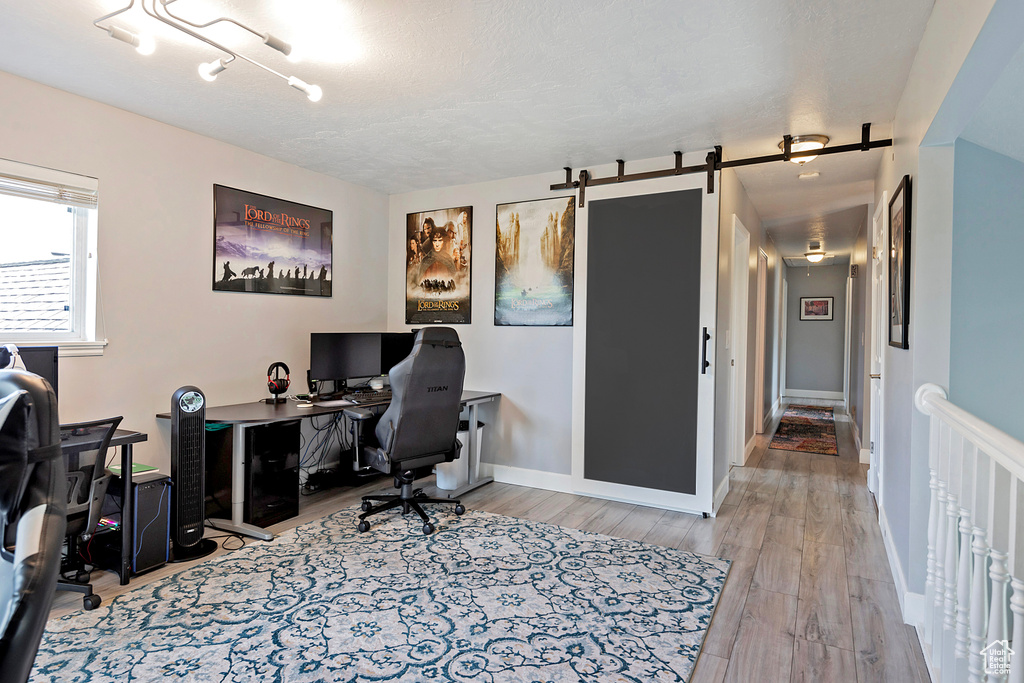 Home office featuring wood finished floors, a barn door, and baseboards