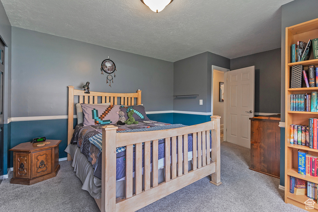 Carpeted bedroom featuring a textured ceiling and baseboards