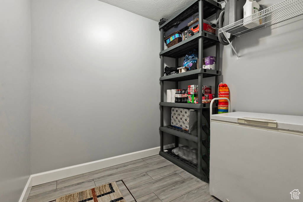 Washroom featuring light wood finished floors, a textured ceiling, and baseboards