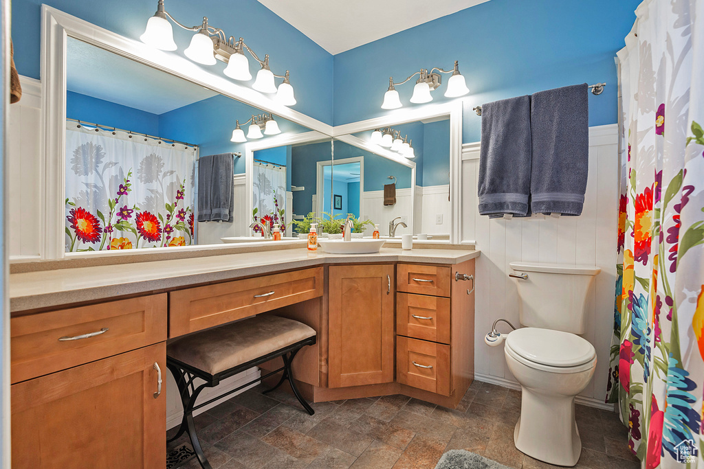 Full bathroom featuring toilet, vanity, stone finish floor, and a shower with shower curtain