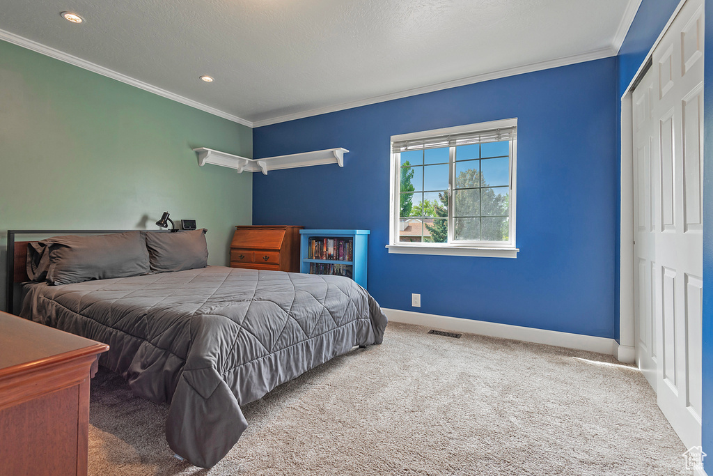 Carpeted bedroom with a closet, recessed lighting, baseboards, visible vents, and crown molding
