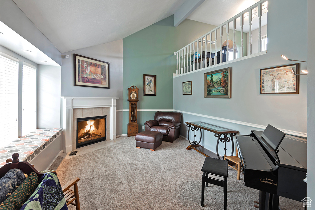 Living area featuring beam ceiling, high vaulted ceiling, carpet floors, baseboards, and a tile fireplace