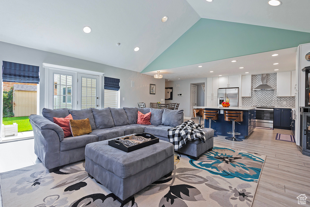 Living room with light wood-style floors, recessed lighting, and high vaulted ceiling