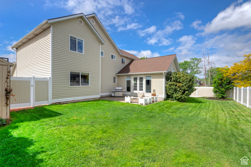 Rear view of house with a fenced backyard, a patio, and a lawn