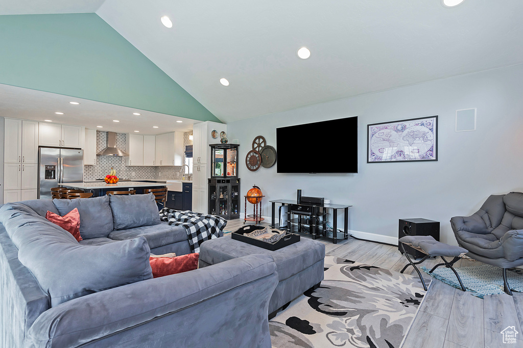 Living room featuring light wood-type flooring, high vaulted ceiling, baseboards, and recessed lighting