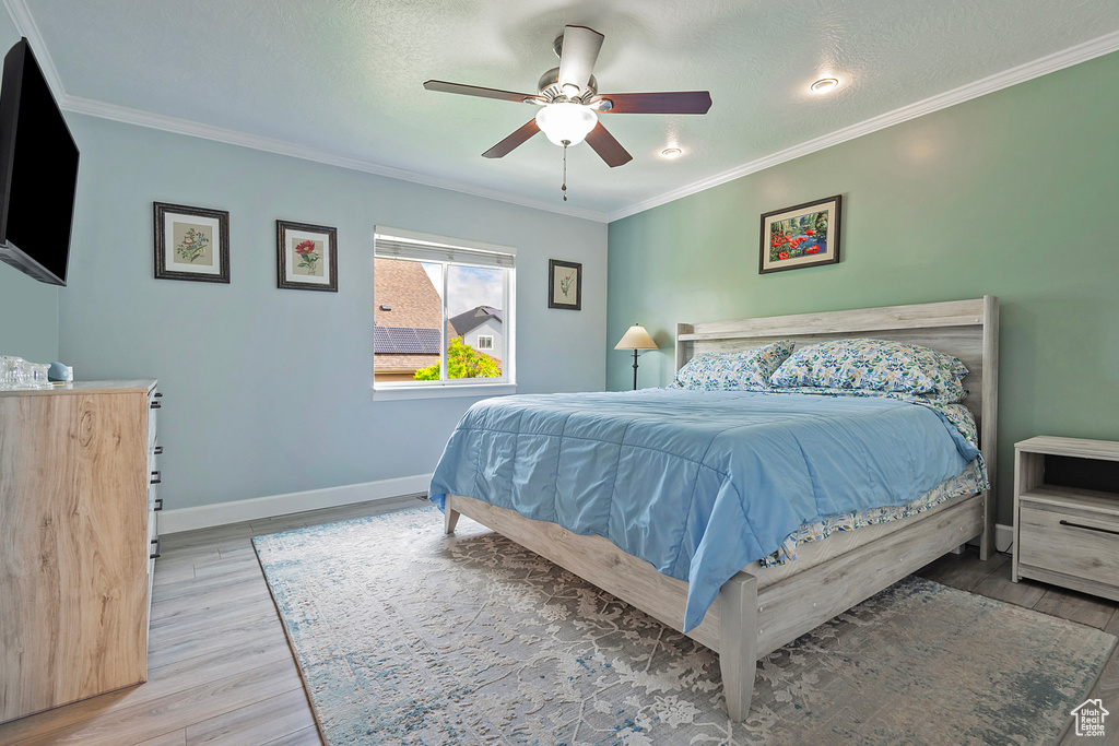 Bedroom featuring baseboards, ornamental molding, a ceiling fan, and wood finished floors