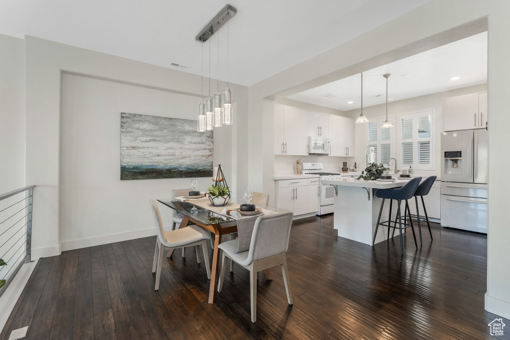 Dining area featuring dark wood-style floors, baseboards, and recessed lighting