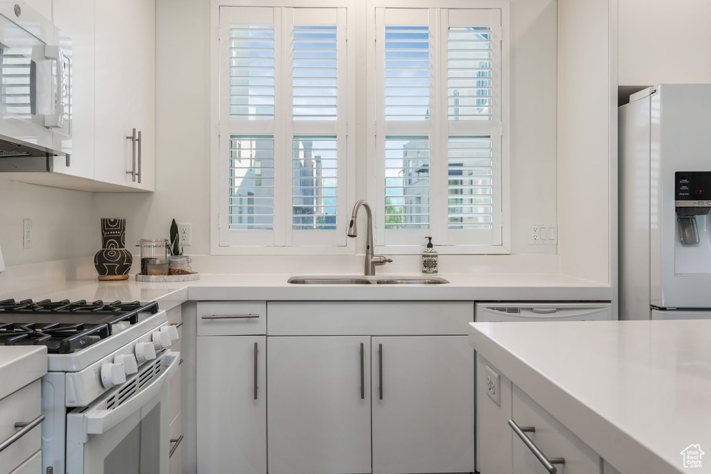 Kitchen featuring white appliances, a sink, light countertops, and white cabinets