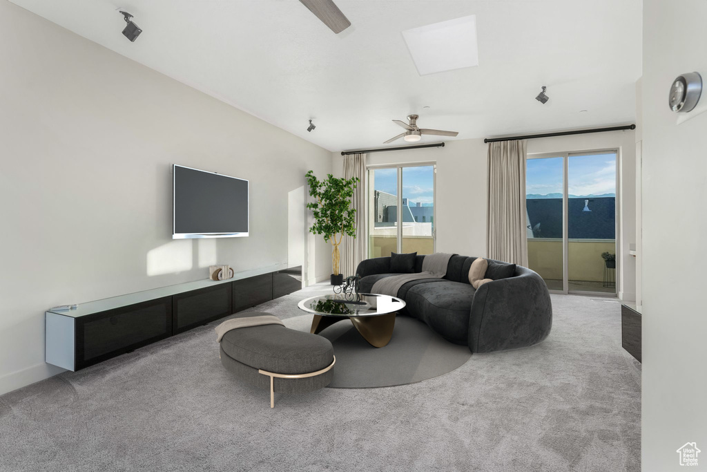 Carpeted living area with ceiling fan and a skylight