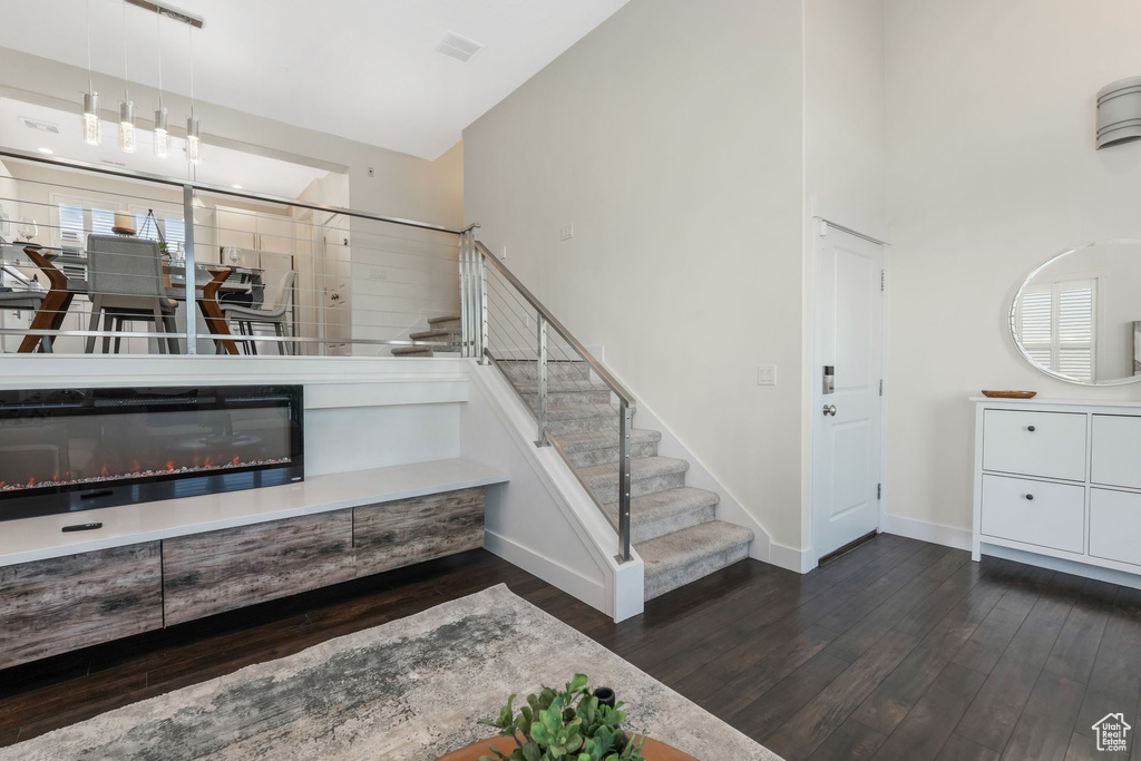 Staircase featuring wood finished floors, baseboards, and a towering ceiling