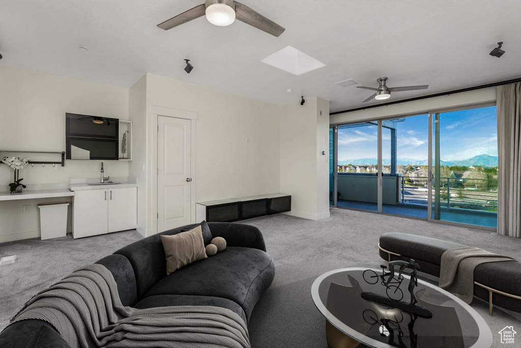 Living area with ceiling fan and light carpet