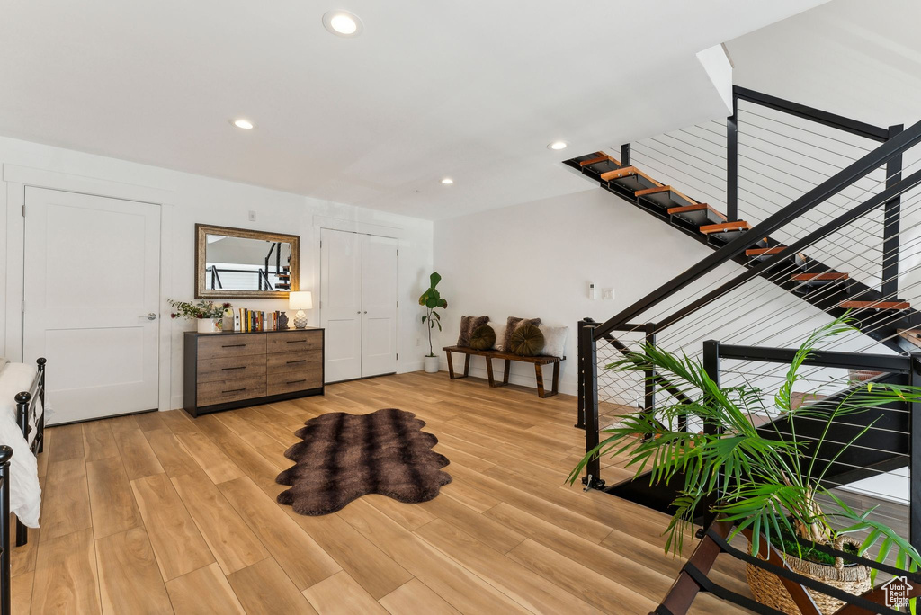 Sitting room with light wood finished floors, recessed lighting, and stairway