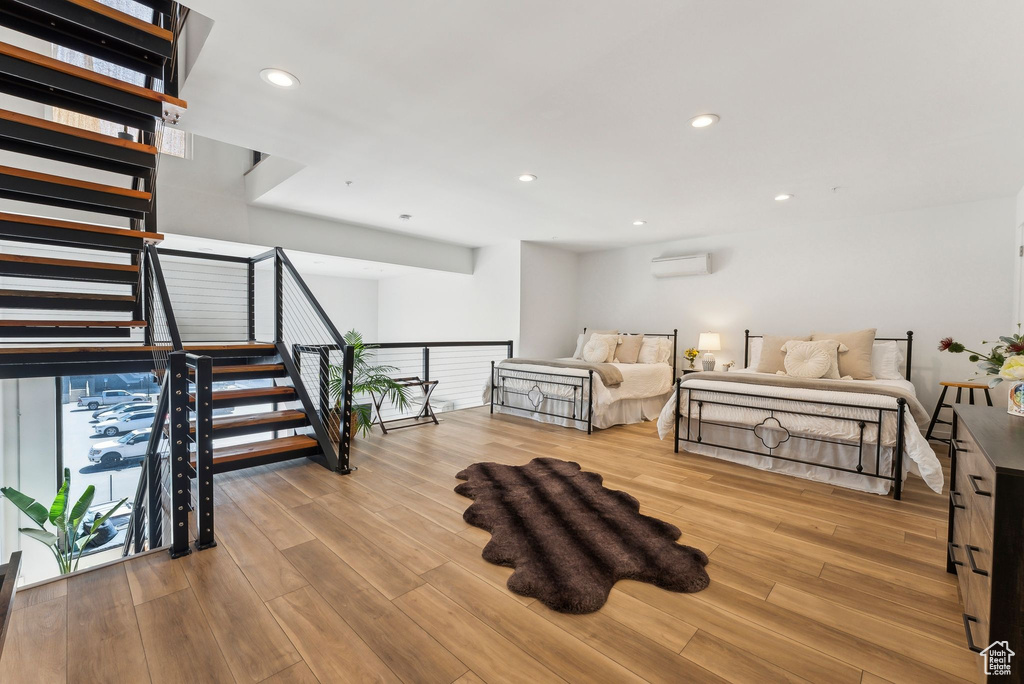 Living area featuring a wall unit AC, wood finished floors, recessed lighting, and stairs
