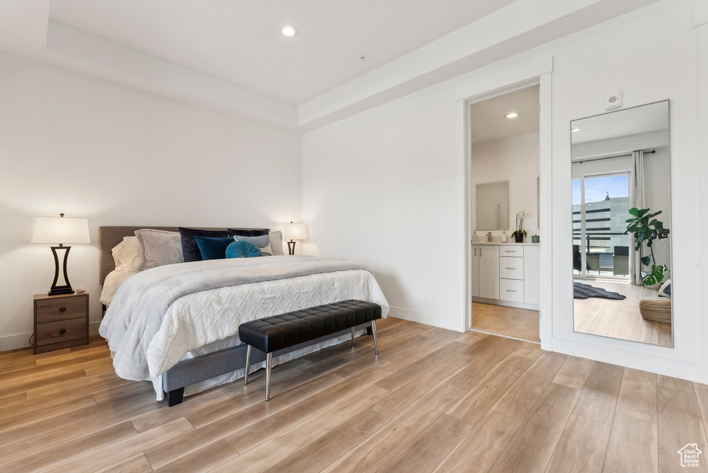 Bedroom featuring light wood-style flooring, recessed lighting, baseboards, and ensuite bath