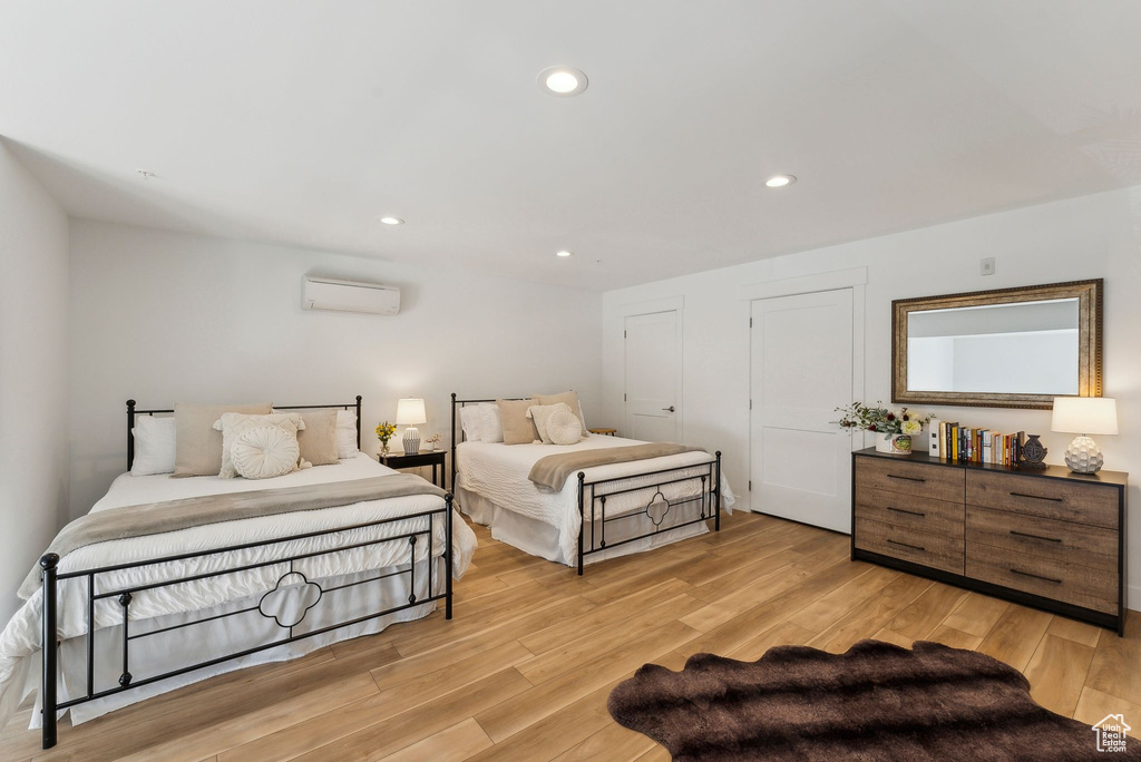 Bedroom featuring light wood-type flooring, a wall unit AC, and recessed lighting