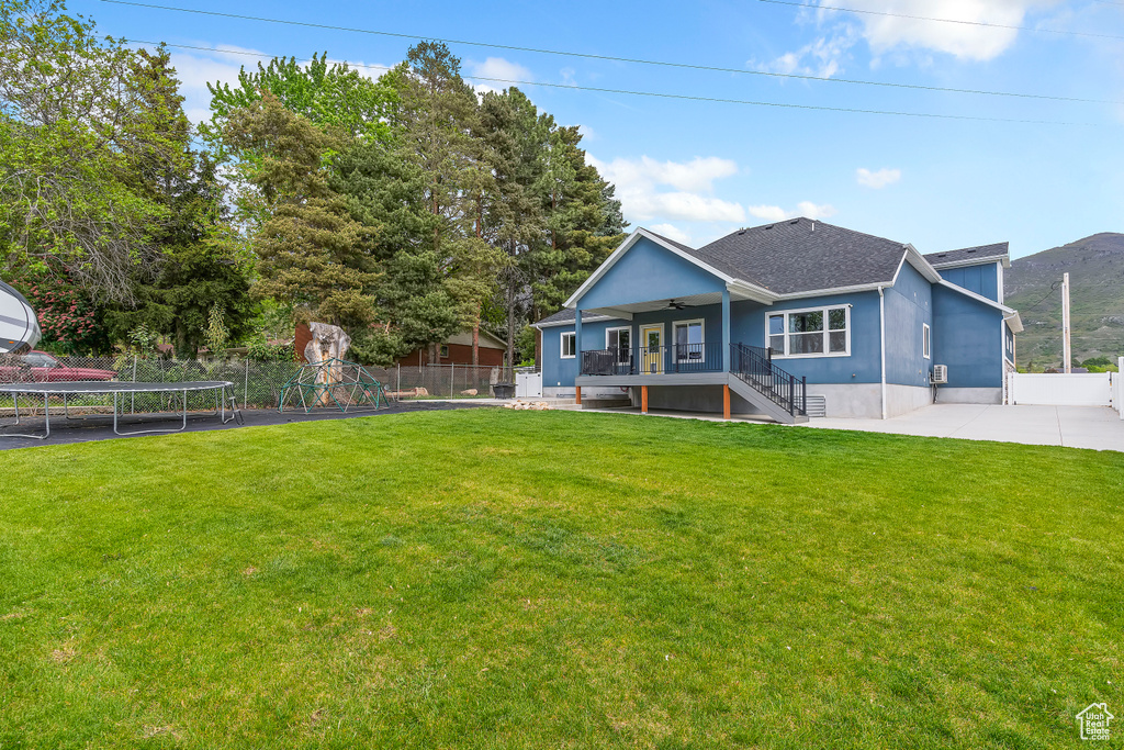Rear view of property featuring a trampoline, a ceiling fan, stairway, and roof with shingles