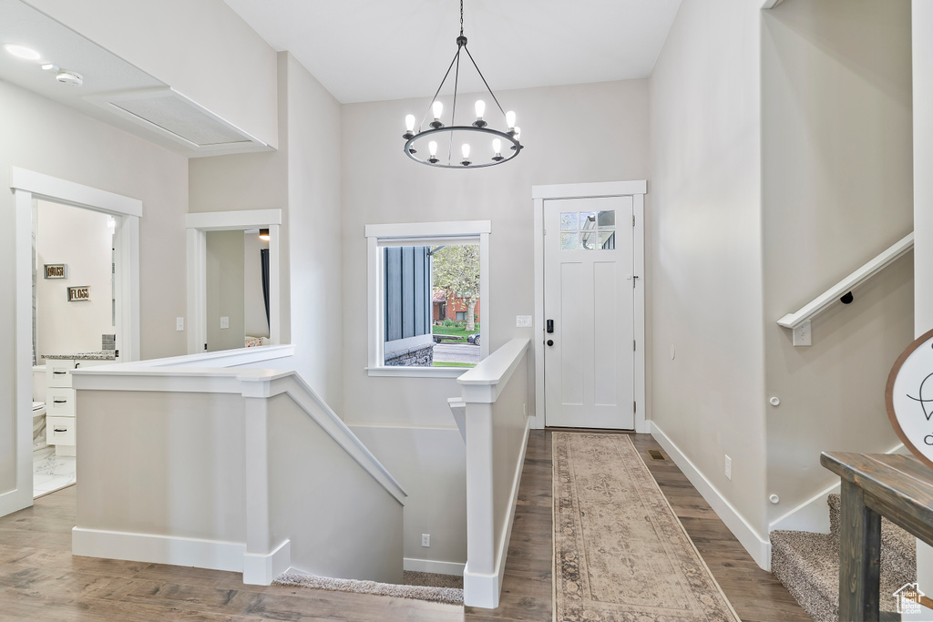 Entrance foyer featuring dark wood-style flooring, a chandelier, and baseboards