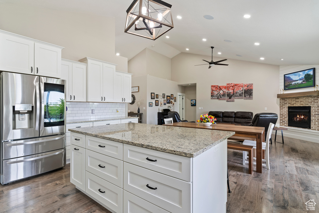 Kitchen with stainless steel fridge with ice dispenser, a kitchen island, high vaulted ceiling, ceiling fan, and open floor plan