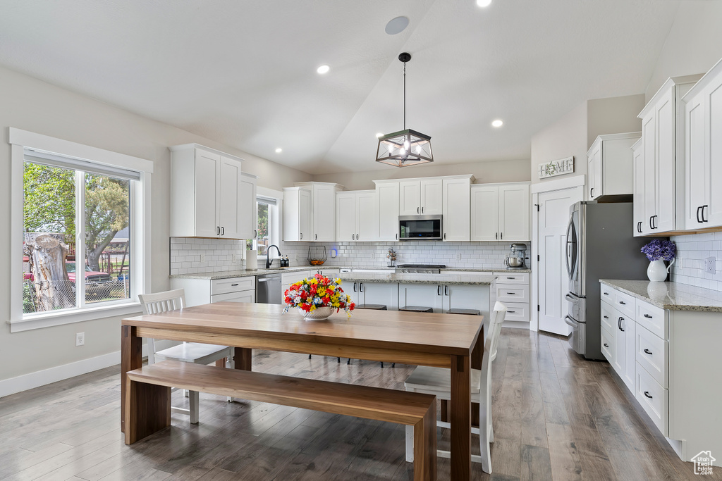 Kitchen featuring stainless steel appliances, white cabinets, healthy amount of natural light, vaulted ceiling, and recessed lighting