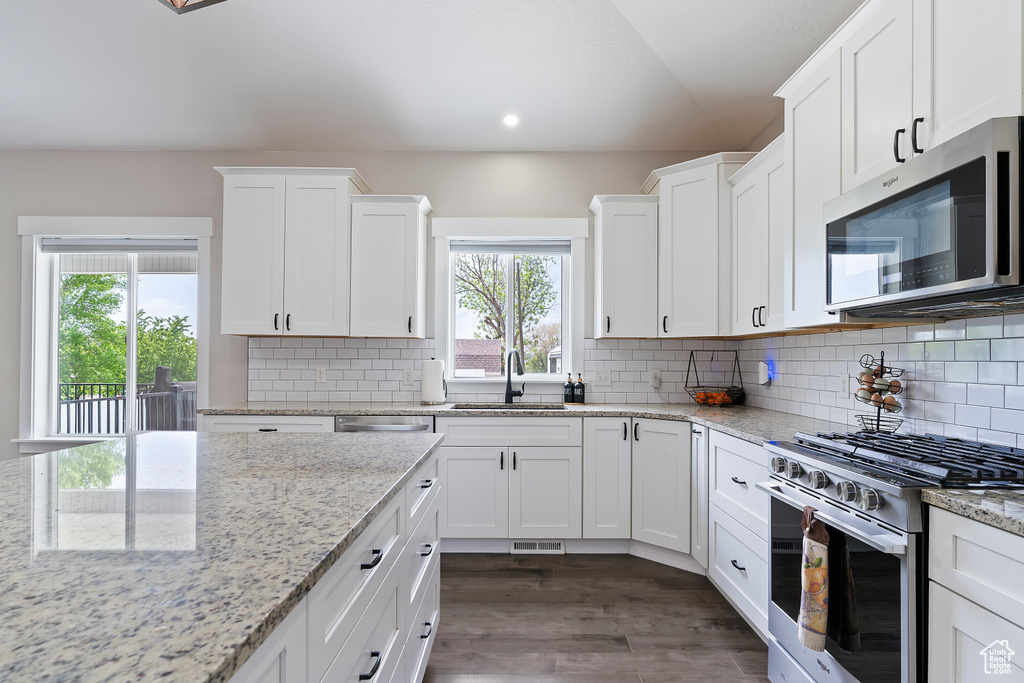 Kitchen with appliances with stainless steel finishes, a sink, white cabinetry, recessed lighting, and dark wood-style flooring