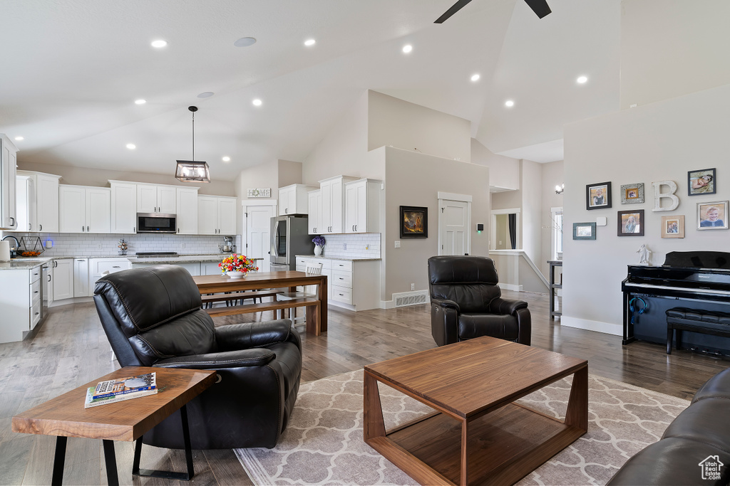 Living area with a ceiling fan, high vaulted ceiling, light wood finished floors, and recessed lighting
