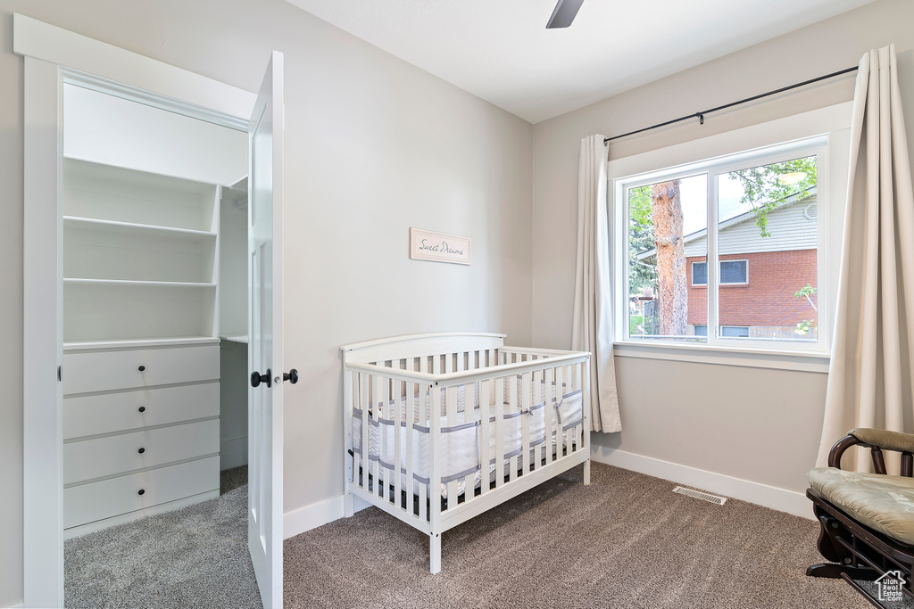 Bedroom featuring carpet floors, baseboards, and a nursery area