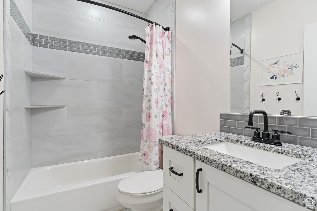 Full bathroom with shower / bathtub combination with curtain, toilet, vanity, and tasteful backsplash