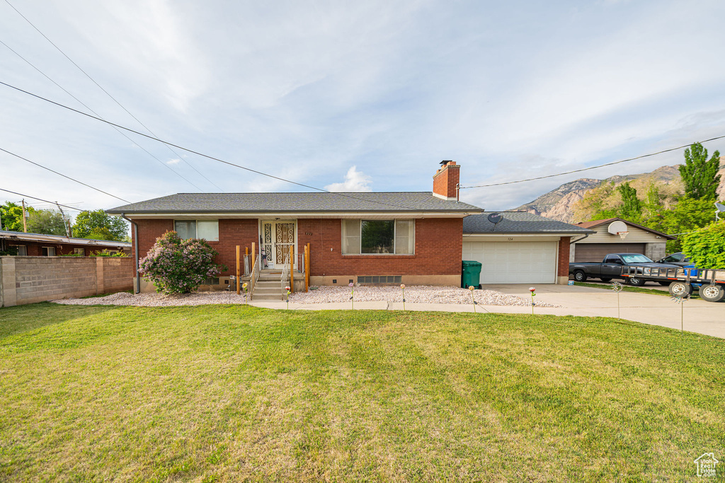 Ranch-style home with a garage, concrete driveway, brick siding, a chimney, and a mountain view