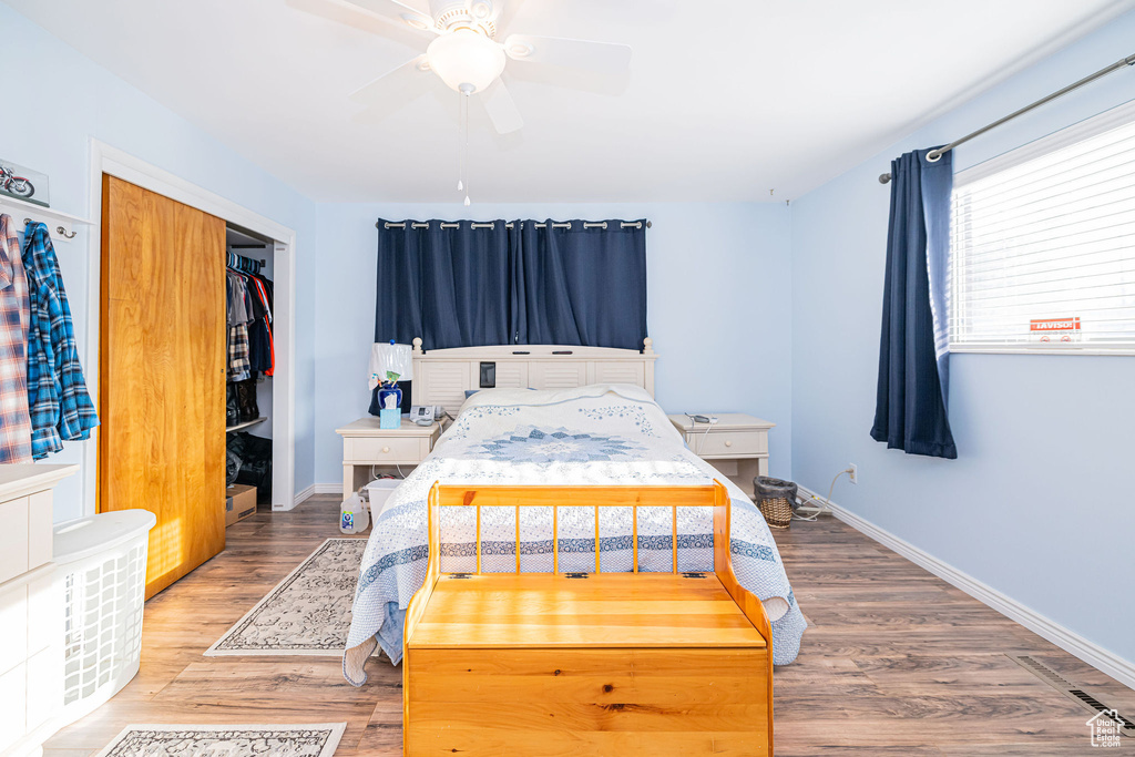 Bedroom featuring wood finished floors, a closet, baseboards, and a ceiling fan