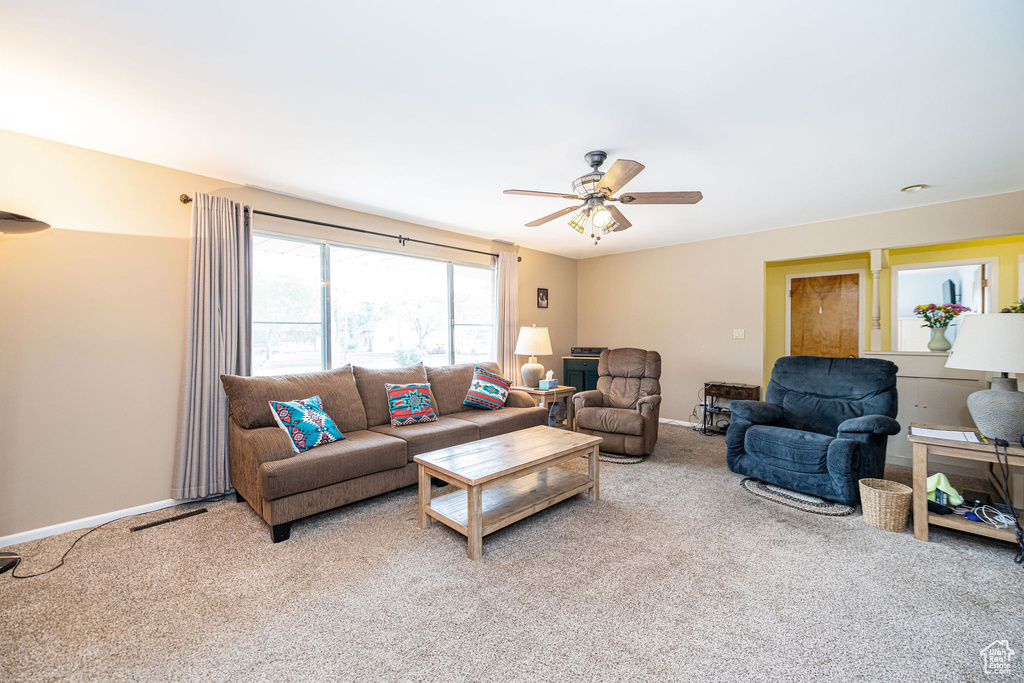 Living area featuring carpet floors, a ceiling fan, and baseboards