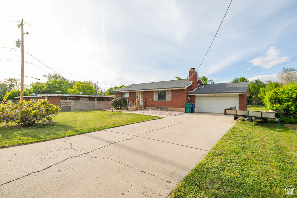 Ranch-style house with brick siding, a front yard, driveway, an attached garage, and a chimney